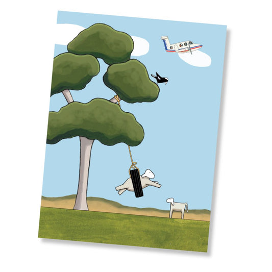 A greeting card featuring a whimsical illustration of a tree with a hanging black tyre swing, a small RFDS plane in the sky, a magpie, and two white sheep on a grassy hill under a light blue sky.