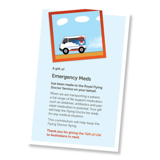 A card for a donation of emergency meds, shown at an angle on a white background. The card has a pale blue field, a small illustrated header with an ambulance, and a red-orange border, and text stating it is a gift of emergency meds and a that it is a donation to the Royal Flying Doctor Service.
