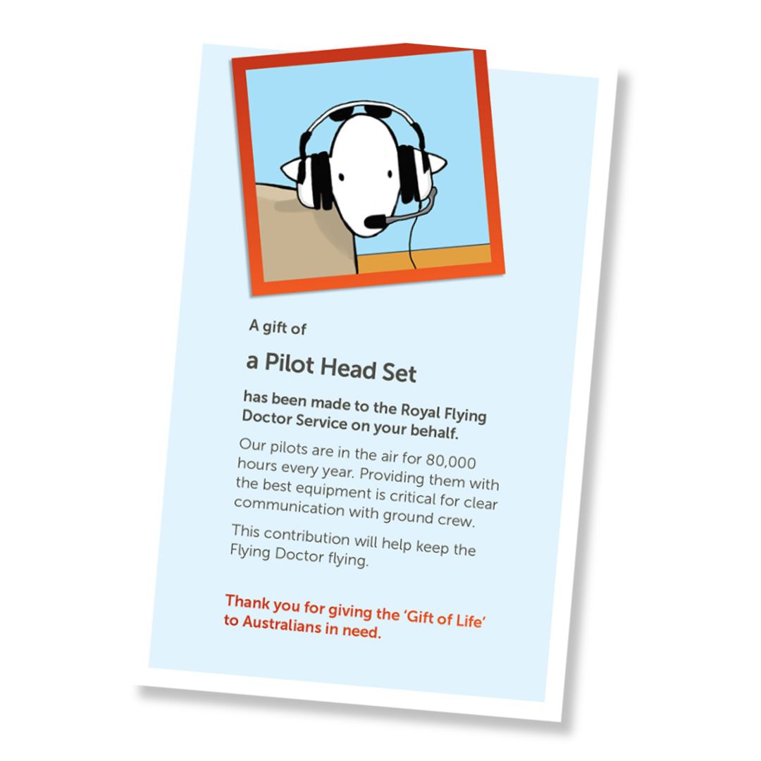 A card for a donation of a pilot head set, shown at an angle on a white background. The card has a pale blue field, a small illustrated header with a sheep wearing a pilot head set, and a red-orange border, and text stating it is a gift of a pilot head set and a that it is a donation to the Royal Flying Doctor Service.
